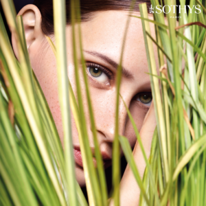 photo of womans face with clear complexion peering through grass